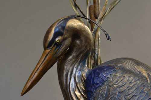 Bronze sculpture by Jim Green of a Great Blue Heron walking in the cattails