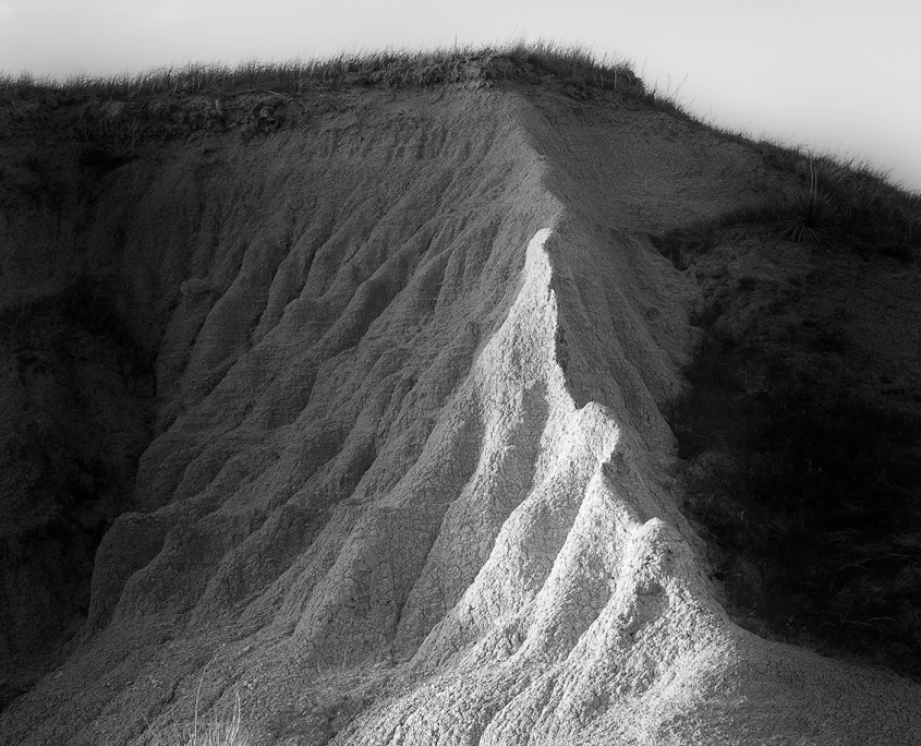 This photo was taken by Amy Lehman in the Badlands of South Dakota. A shaft of setting sun illuminated this badlands bank and highlights the rippling pattern of erosion.